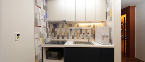 A compact kitchen with a microwave, sink, and a built-in oven.