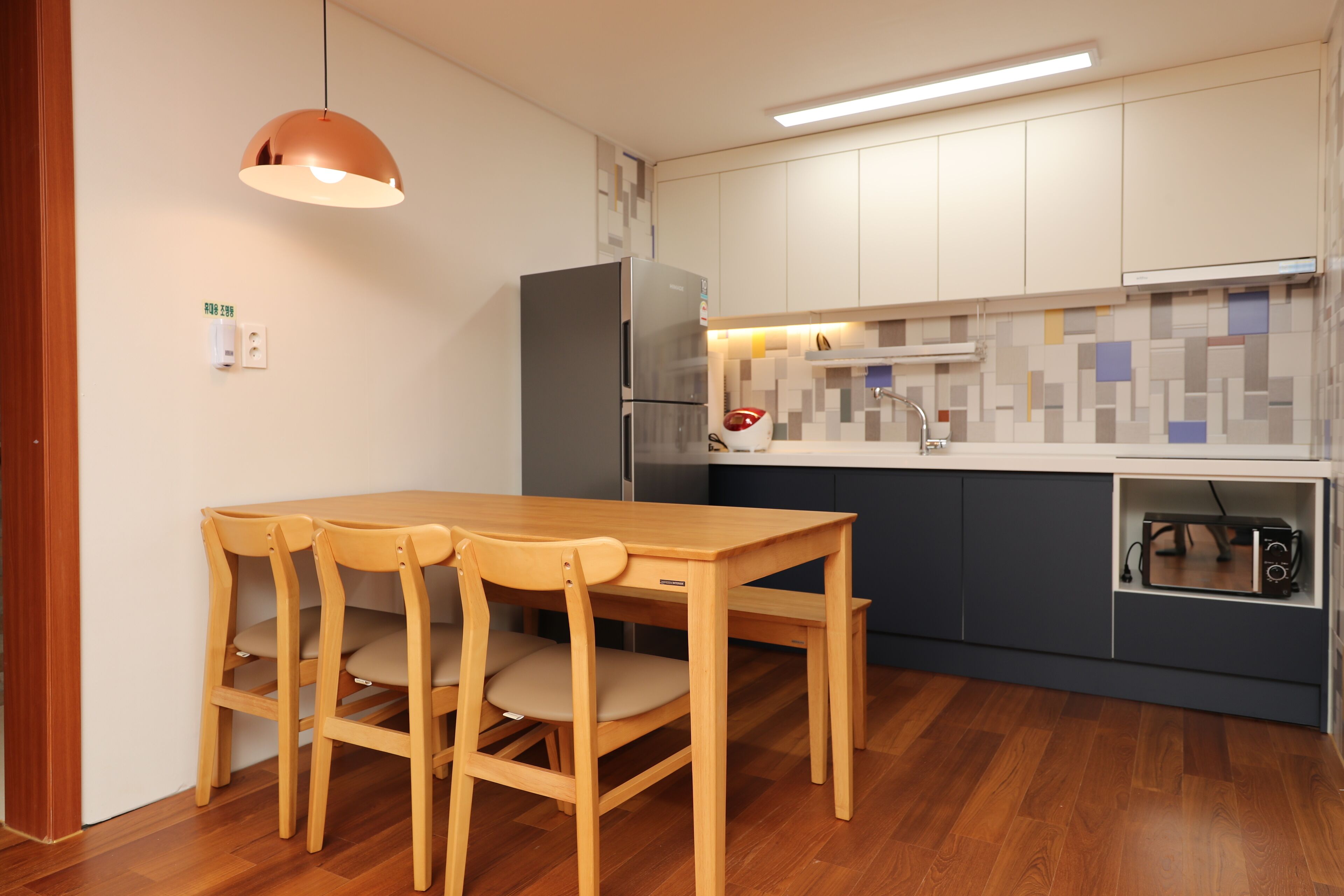 A compact kitchen with a wooden dining table and chairs, a built-in oven, and a microwave.