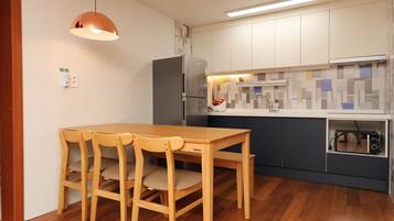 A compact kitchen with a wooden dining table and chairs, a built-in oven, and a microwave.