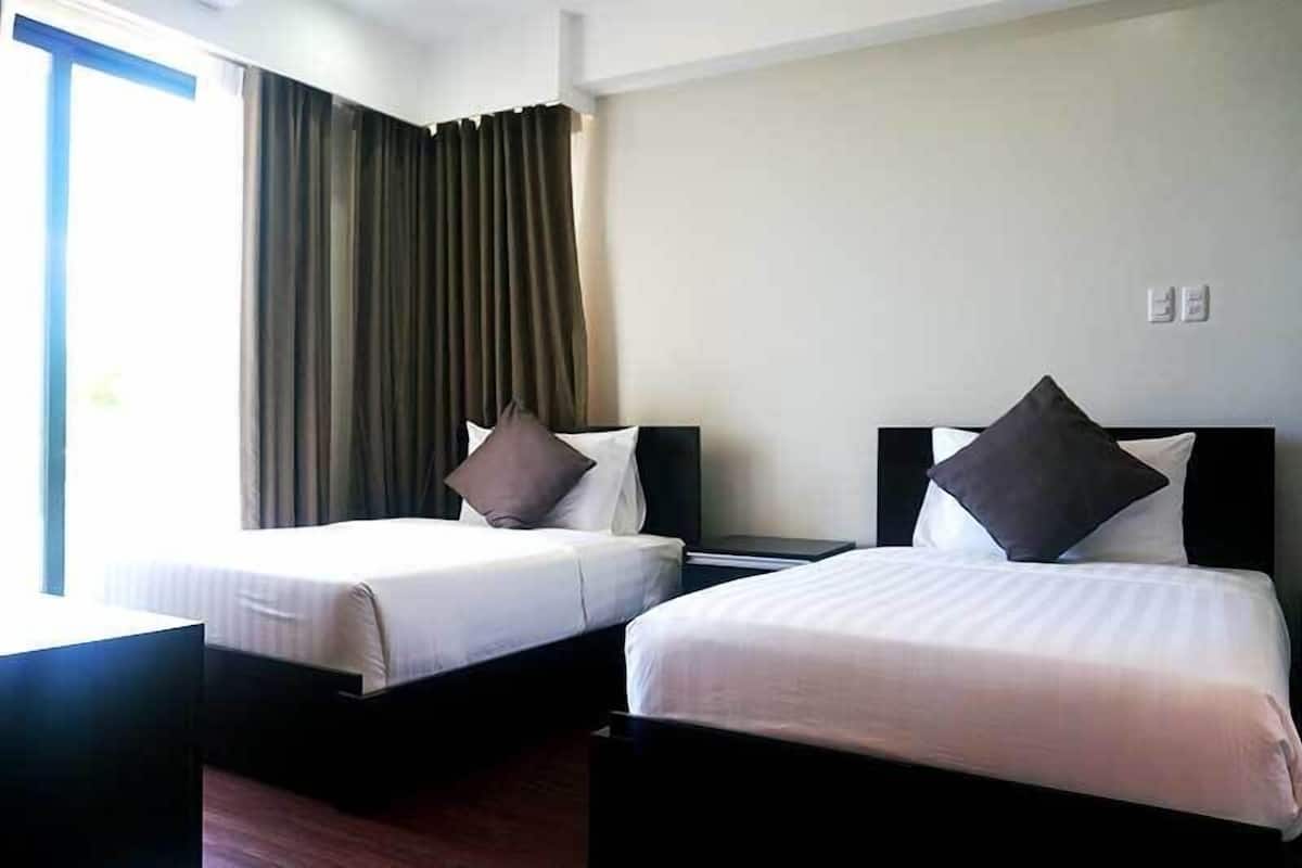 Two single beds with white linens and dark headboards in a hotel room.