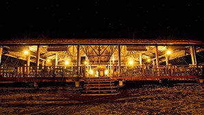 A beachside wooden structure with multiple seating areas and a central staircase, illuminated by overhead lights. - Aqua Fun Hotel (Mariveles)