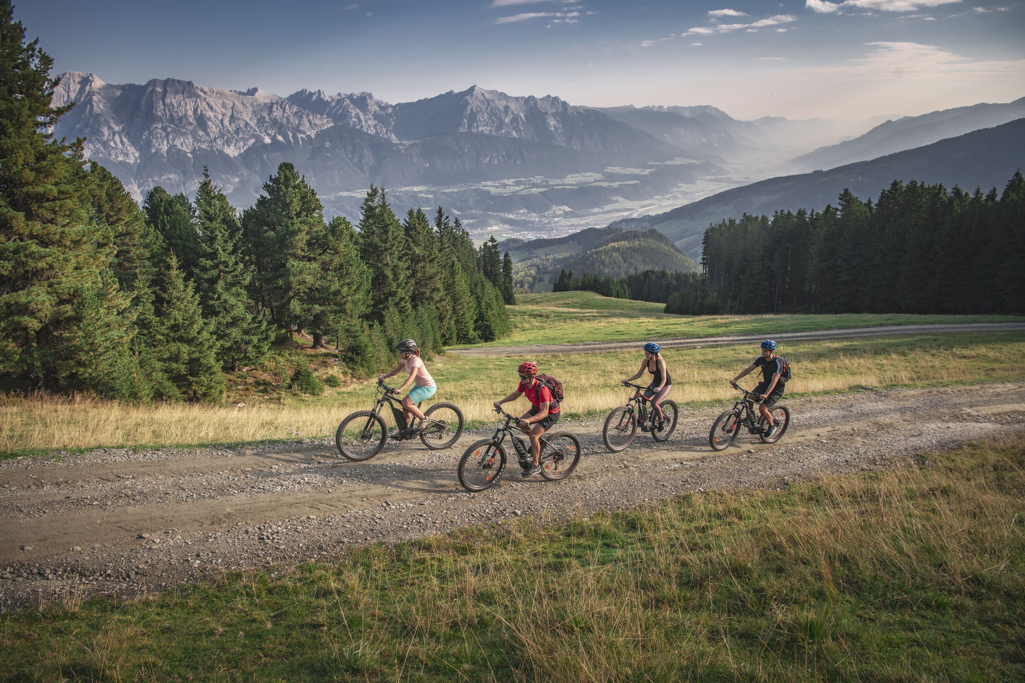 Eine Gruppe Radfahrer auf einem Schotterweg vor einer Bergkulisse.