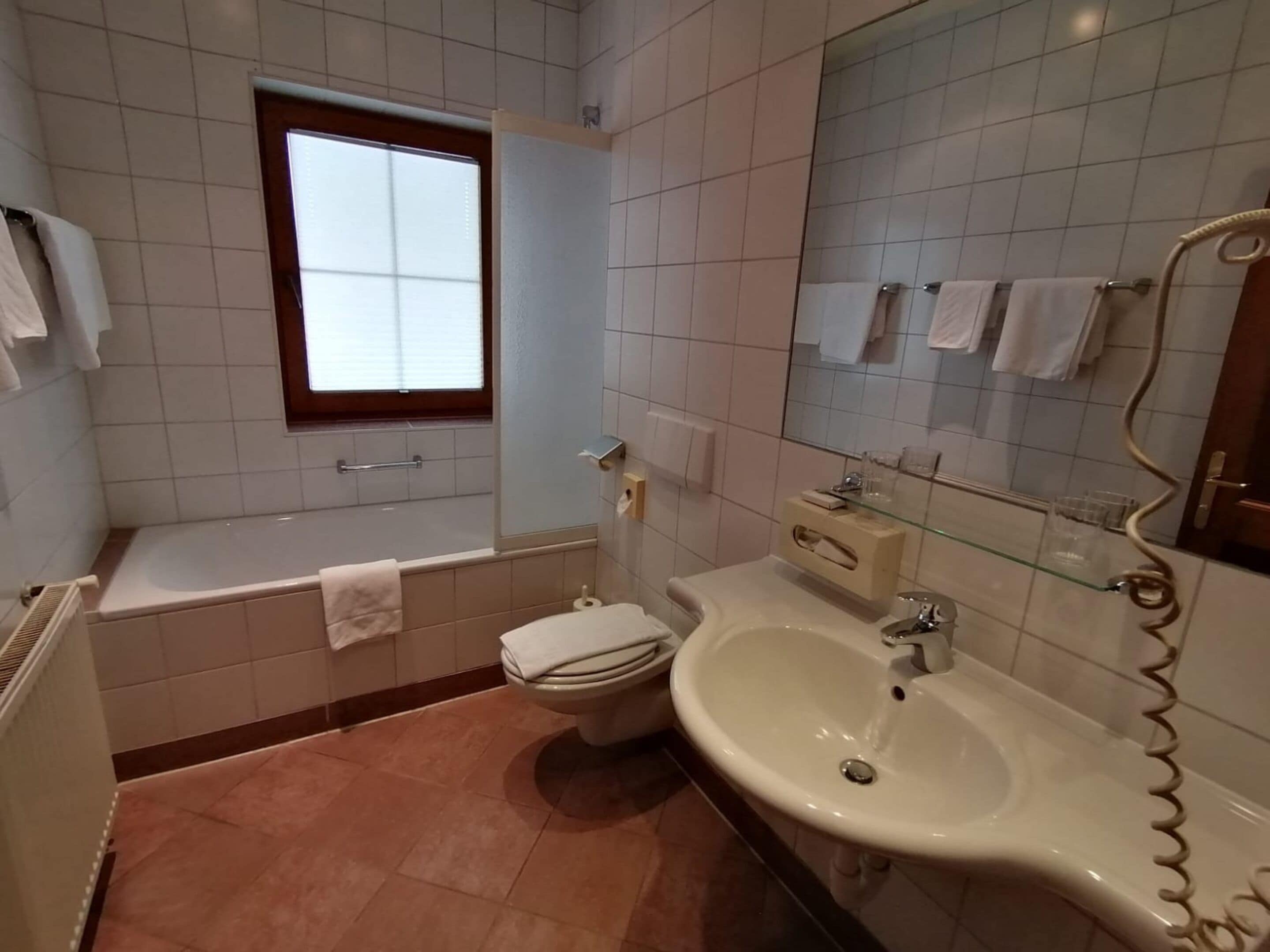Un baño con bañera, inodoro, lavabo y ventana.