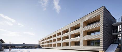 A modern multi-story building with a flat roof and a series of balconies.