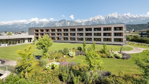Un bâtiment moderne doté d’un toit plat, de nombreuses fenêtres et d’un jardin aménagé avec diverses plantes et fleurs.