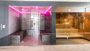 Une salle de bain moderne avec une paroi en verre, un banc et un espace sauna en bois.