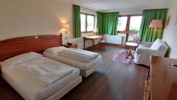 Habitación de hotel con dos camas, un escritorio, una silla y un sofá.
