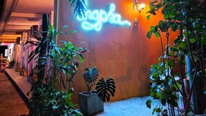 A building with a neon sign reading "ngopa" and a well-lit entrance.