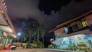 A building with a mural, a parked scooter, and a palm tree.