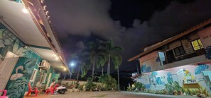 A building with a mural, a parked scooter, and a palm tree.