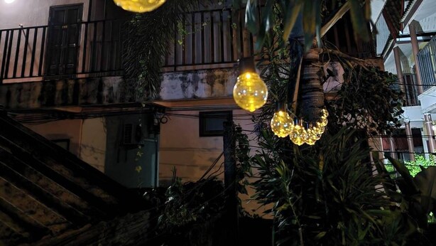 A building with a balcony, a staircase, and hanging spherical lights.