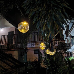A building with a balcony, a staircase, and hanging spherical lights.
