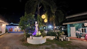A courtyard with a statue, outdoor seating, and a building with a mural.