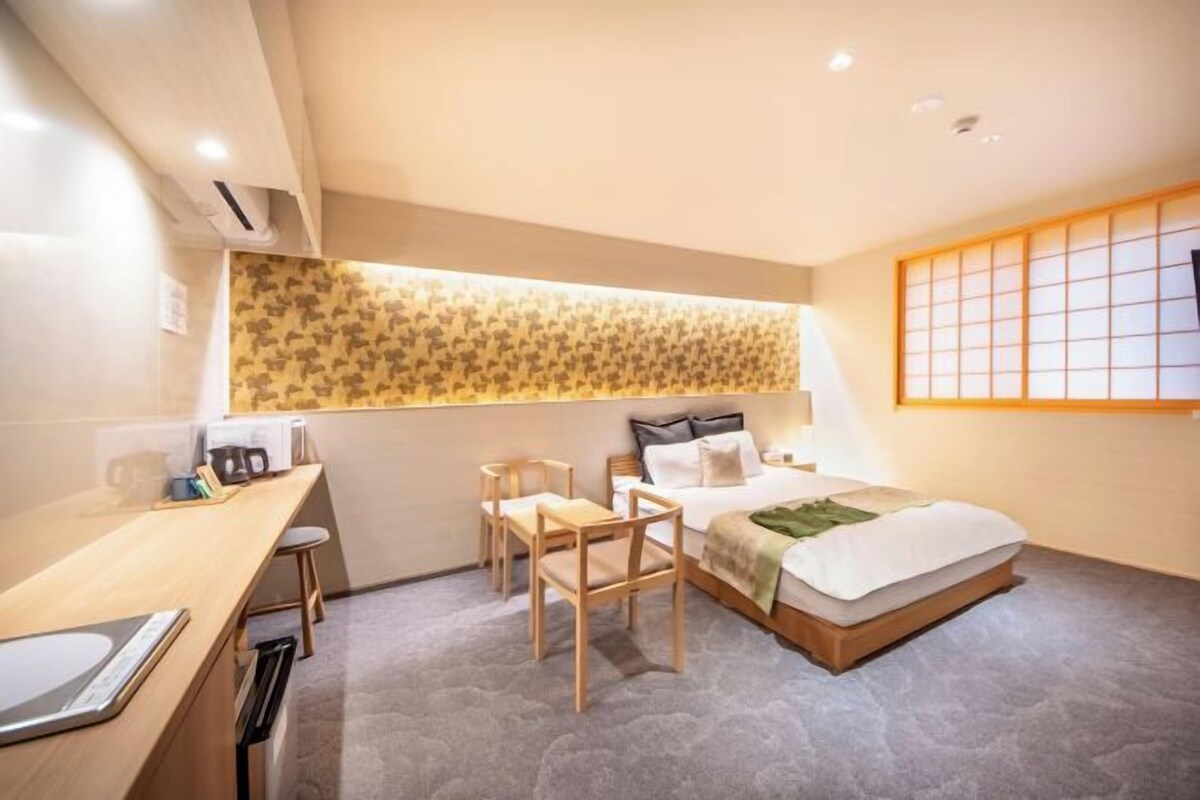 Habitación de hotel con cama, escritorio, sillas y ventana con vistas.