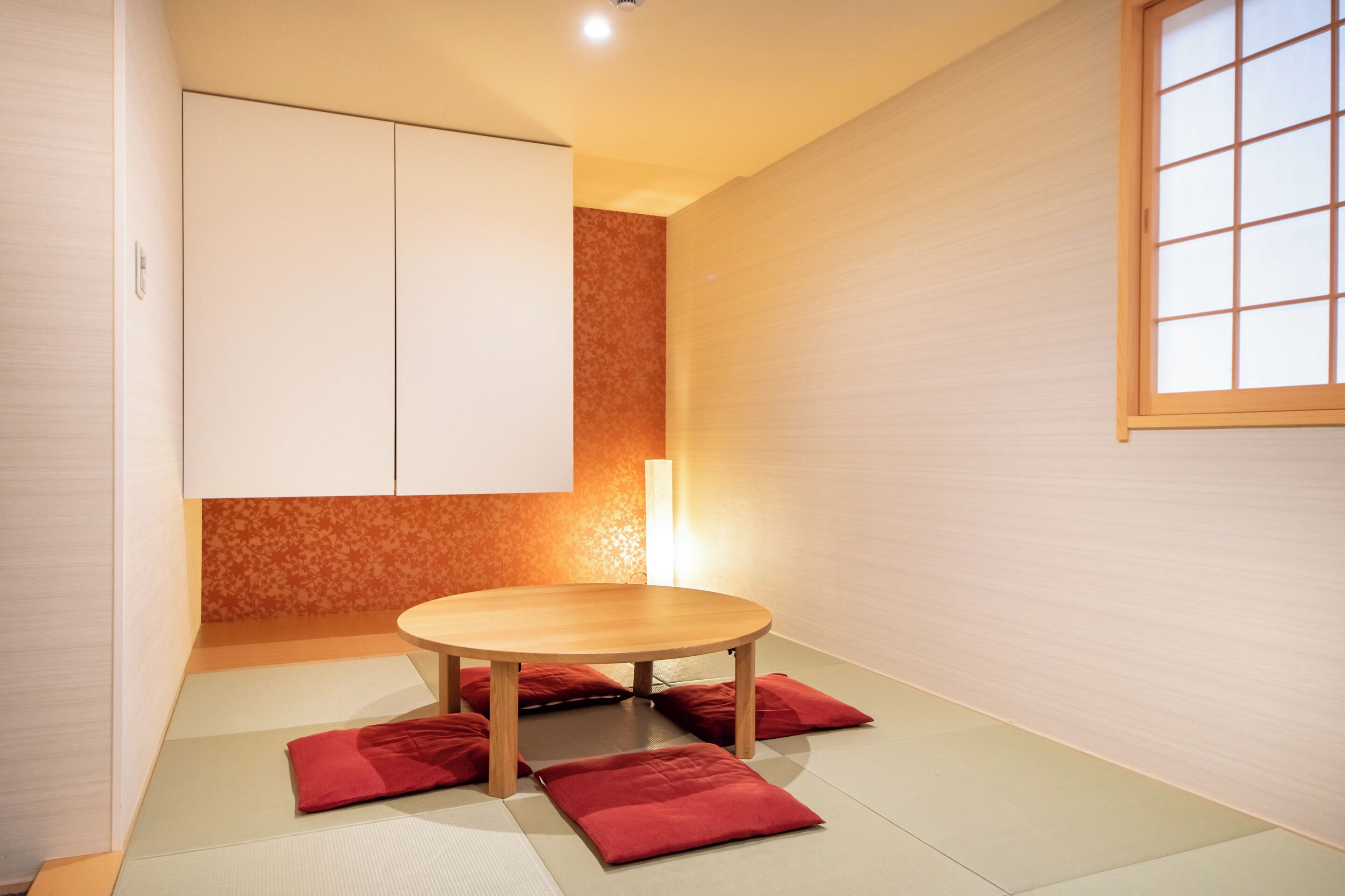 A room with tatami mats, a wooden table, and red cushions.