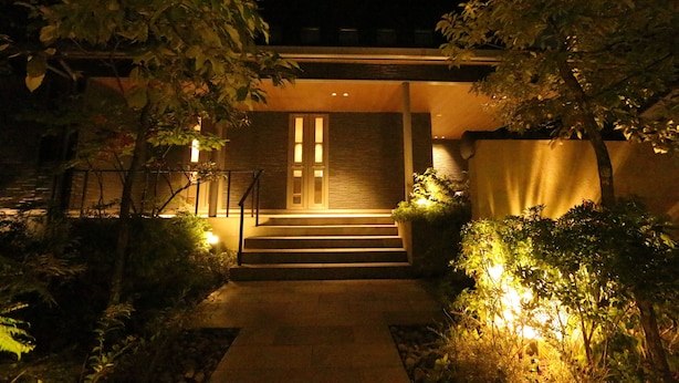 Une maison moderne dotée d’une entrée bien éclairée, d’un escalier et d’un jardin.