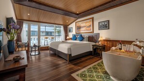 Un dormitorio amplio con una cama grande, una zona de estar con un ordenador portátil, una bañera y vistas al exterior.