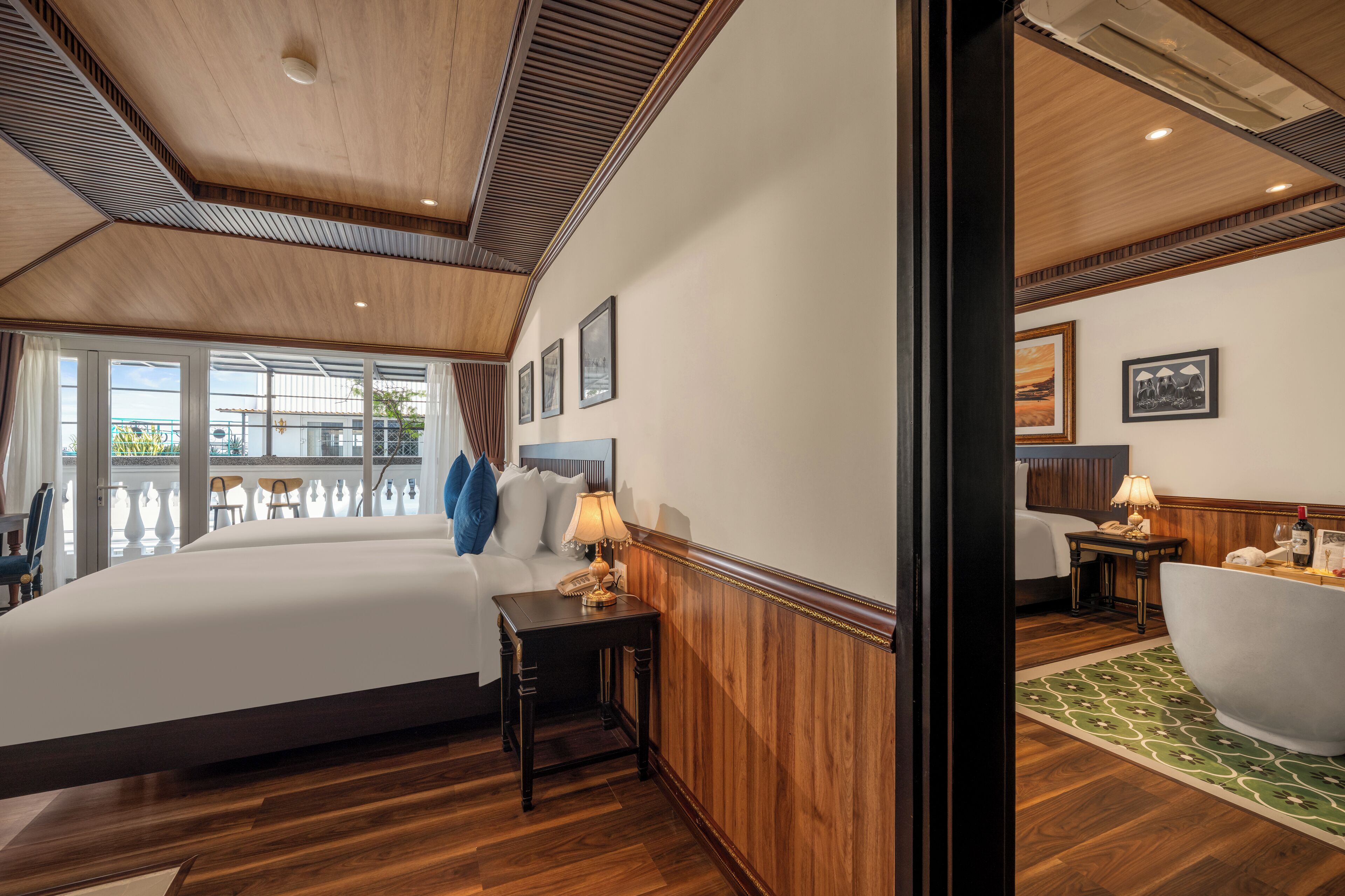 A hotel room with a large bed, a sitting area with a table and chairs, a bathtub, and a view of the outdoors.
