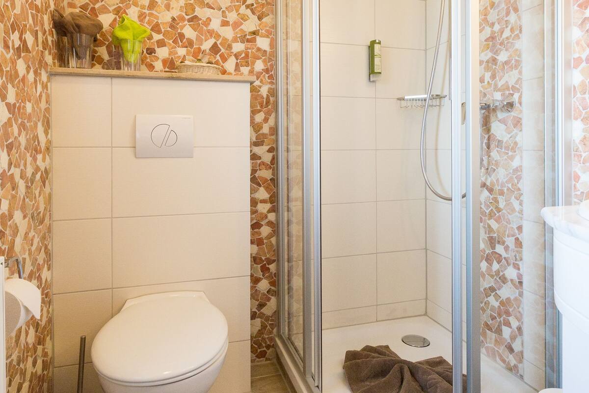 Un baño con ducha, inodoro y un trapeador.