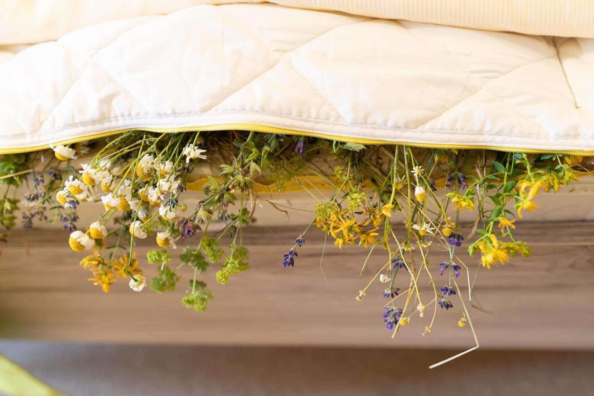 A bed with a quilted mattress and a yellow-striped pillow.