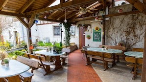 An outdoor patio with wooden tables and benches, a brick pathway, and potted plants. - Kräuterhotel Garni zur Klostergrotte (Grammetal)