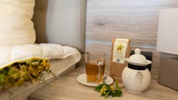 Una mesa de madera con una taza de té, una tetera, un paquete de té y un almohadón.