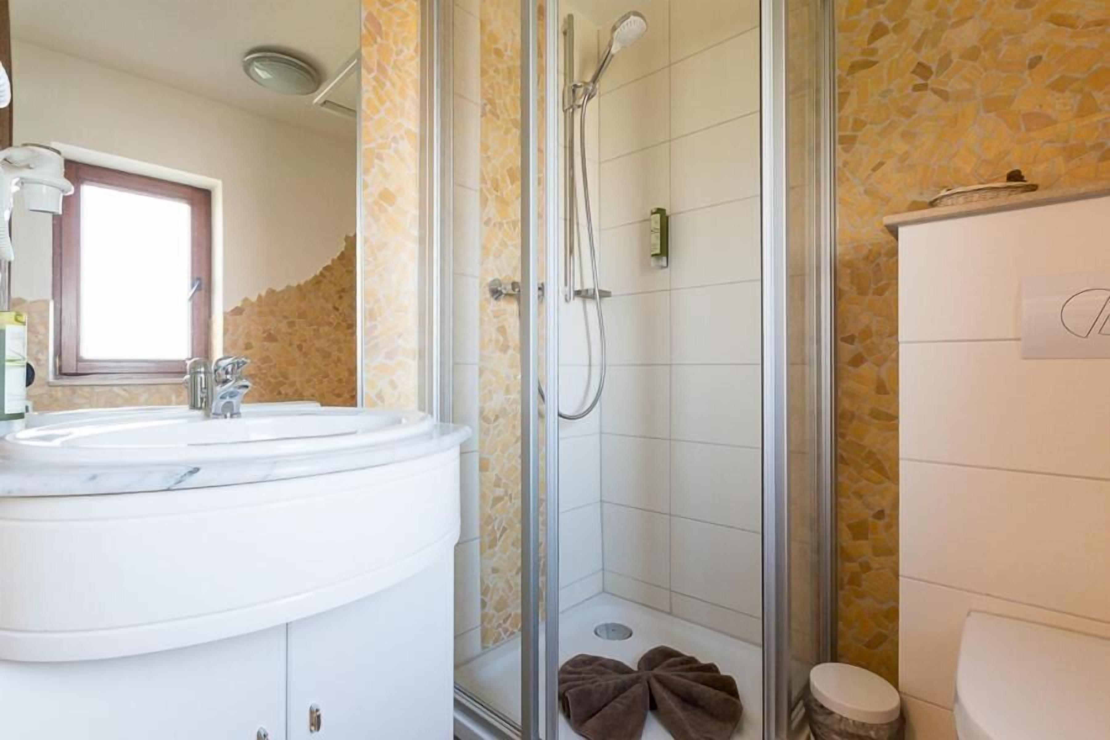 A bathroom with a glass-enclosed shower, a sink with a mirror, and a toilet.