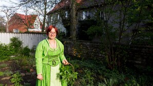 A person standing in a garden with a house in the background. - Kräuterhotel Garni zur Klostergrotte (Grammetal)