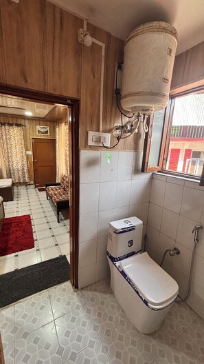 A bathroom with a toilet, shower, and a window. - Hotel Ekant Lodge (Dharamshala)