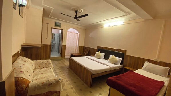 Habitación de hotel con cama, sofá, escritorio y zona de ducha.