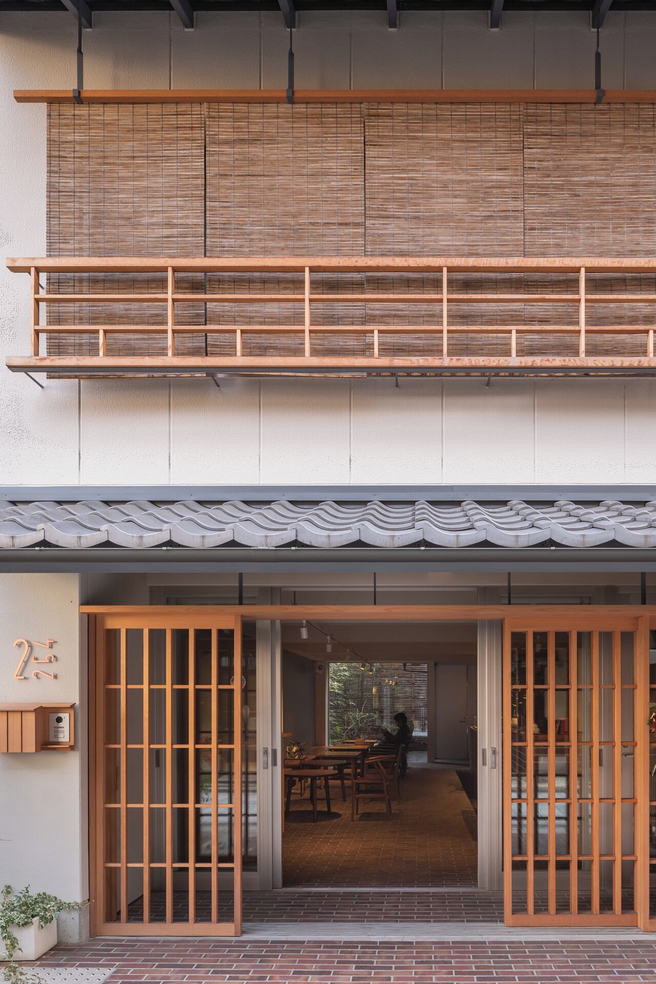 Un bâtiment à deux étages de style architectural japonais traditionnel, doté d’un balcon en bois et de portes coulissantes.