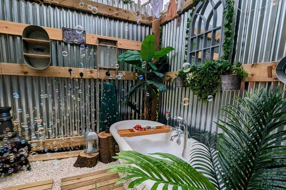 Un baño rústico al aire libre con una terraza de madera, una bañera y un letrero que indica lavandería.
