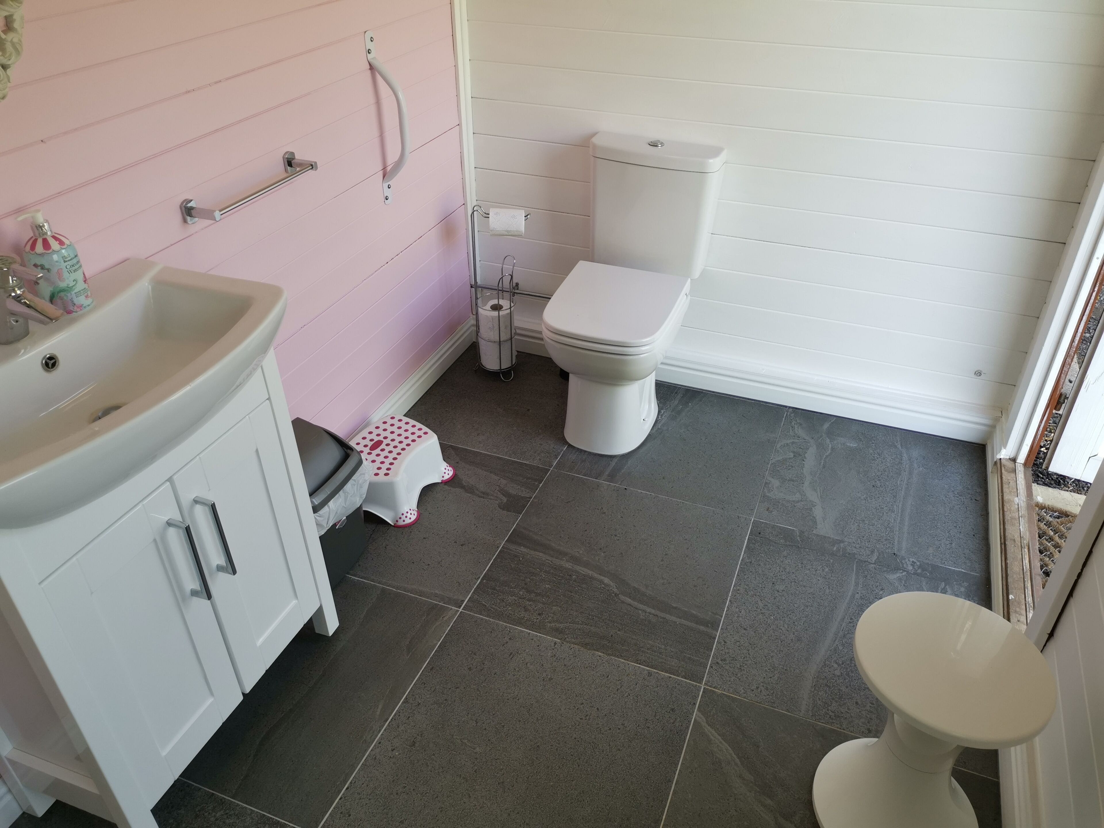A bathroom with a white sink, a toilet, and a small step stool.