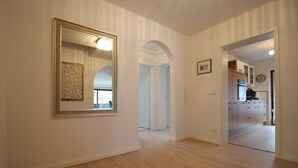 Um corredor com piso de madeira, um espelho grande e uma obra de arte emoldurada na parede.