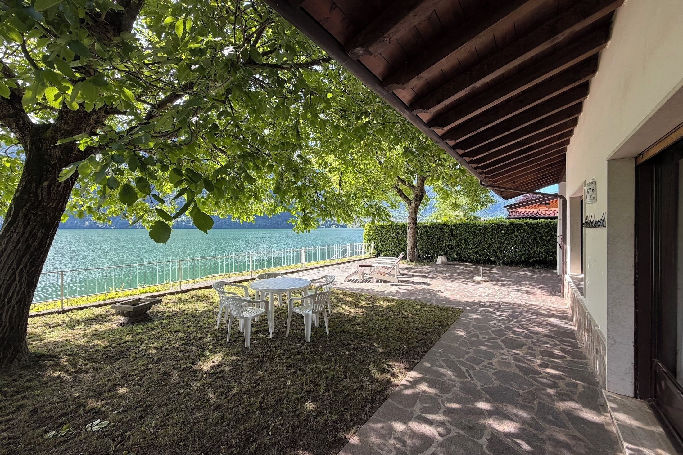 Une terrasse avec une table et des chaises, un chemin en pierre et une vue sur l’eau.
