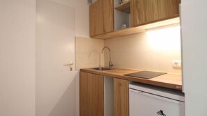 A compact kitchen with wooden cabinets, a built-in dishwasher, and a sink with a modern faucet.