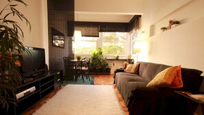 Una sala de estar con televisor, sofá y comedor.