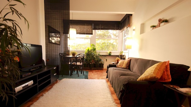 Ein Wohnzimmer mit Fernseher, Sofa und Essbereich.