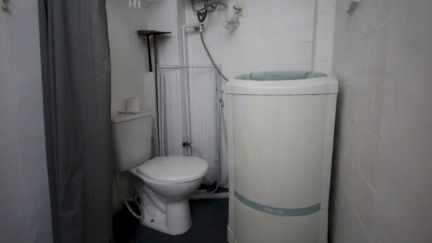 Un baño pequeño y funcional con inodoro blanco, cabina de ducha y lavamanos instalado en la pared.
