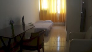 A hotel room with a bed, a small table with a vase, a chair, and a TV. - Gohouse - Laranjeiras 116 (Rio de Janeiro)