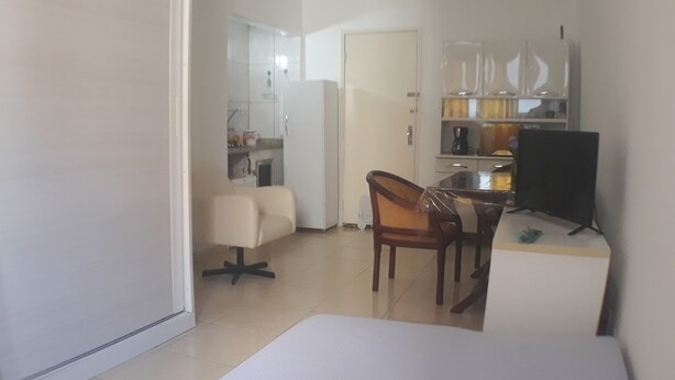 A compact living space with a kitchenette, a dining area with a table and chairs, and a television. - Gohouse - Laranjeiras 116 (Rio de Janeiro)