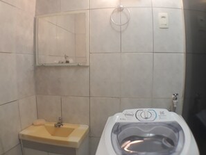 Ein Badezimmer mit Waschbecken, Spiegel und Waschmaschine.