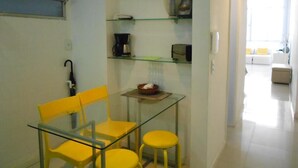 A small kitchen with a glass table and chairs, a clock, and shelves with various items. - Gohouse - Copacabana 1206 (Rio de Janeiro)