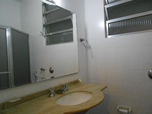 Une salle de bain équipée d’un lavabo, d’un miroir et d’une fenêtre avec des barreaux en métal.