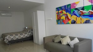 A modern room with a bed, a sofa, and a colorful abstract painting on the wall. - Gohouse - Copacabana 1206 (Rio de Janeiro)