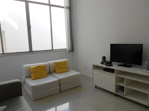 Un salon moderne avec un canapé blanc, un téléviseur à écran plat et un meuble de rangement blanc.