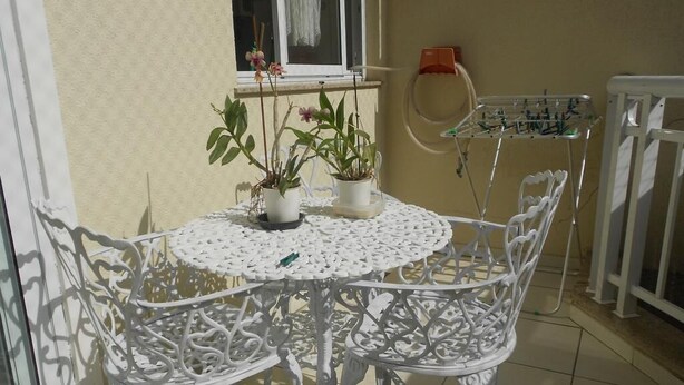 A white wrought iron table and chairs set on a tiled patio with potted plants. - Gohouse - Dutra 102 (Rio de Janeiro)