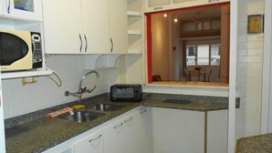 A compact kitchen with white cabinets, a microwave, a toaster, and a sink. - Gohouse - Figueiredo 303 (Rio de Janeiro)