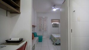 Ein Zimmer mit einem Bett, einem Schreibtisch, einem Stuhl, einem Deckenventilator und einem Fenster.