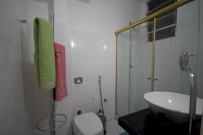 A modern bathroom with a glass-enclosed shower, a white sink, and two towels hanging on a metal rack. - Gohouse - Raul 607 (Rio de Janeiro)